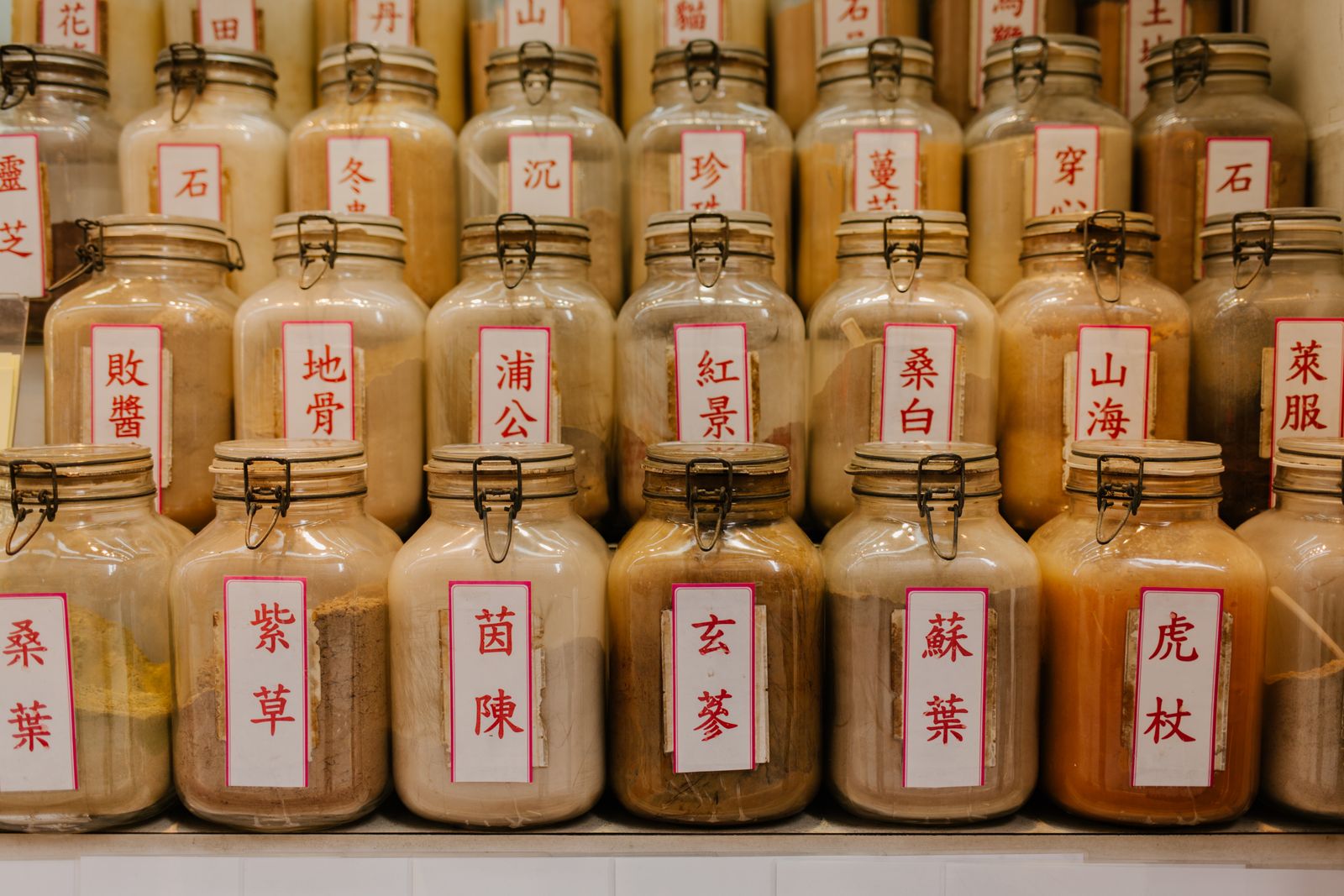 Shelves of glass jars filled with dried herbs, each with a handwritten label